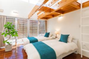 2 Betten in einem Zimmer mit Fenster in der Unterkunft Comfort Villa YAGAJI in Nago