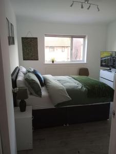 a bedroom with a bed with green sheets and a window at Stourbridge - Dudley - Luxurious 5 Beds - DY2 - Long Stay for Contractors & Families in Woodside