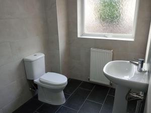 a bathroom with a toilet and a sink and a window at Stourbridge - Dudley - Luxurious 5 Beds - DY2 - Long Stay for Contractors & Families in Woodside