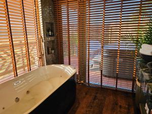 y baño con bañera y ventanas de madera. en Lavish Country Retreat 30mins Taxi Ride From West London, en Chessington