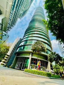 um edifício alto com uma árvore em frente em Vortex suites klcc by Yashrib em Kuala Lumpur