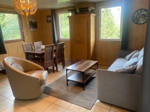 uma sala de estar com um sofá, uma mesa e cadeiras em Gîte Croc Blanc em Sondernach