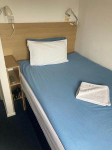 a bed with blue sheets and a white pillow at Hostel Alma in Dover