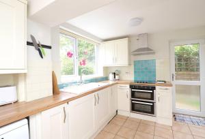 uma cozinha com armários brancos, um lavatório e um fogão em Pass the Keys Victorian 3 Bed inc Parking Garden Headington em Oxford