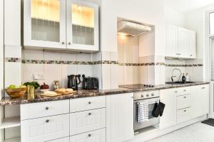 a white kitchen with white cabinets and appliances at Ground Floor En-Suite Room with a Private Kitchen and Parking in a 5-Bedroom House at Hanwell in Hanwell