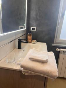 een badkamer met een wastafel met 2 handdoeken en een spiegel bij Le camere del Cappello Verde in Ivrea