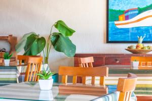 a dining room with a table with chairs and a plant at Pousada dos Coqueiros Búzios in Búzios