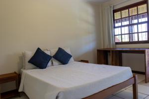 a bedroom with a bed with blue pillows and a window at Pousada dos Coqueiros Búzios in Búzios