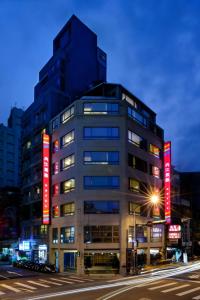 um edifício alto com sinais vermelhos no lado em Nei Jiang Hotel em Taipei
