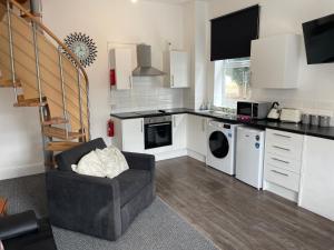 a living room with a kitchen with a couch at Swinefleet Maisonettes. Airy, Modern & Chic! in Goole