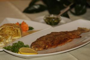 un plato de comida con un trozo de pescado y verduras en Guest House and Museum Firšt en Solčava