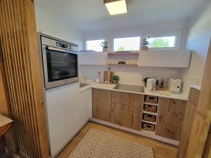 a small kitchen with white appliances and wooden cabinets at Faház a kilátónál Woodhouse Lux near Kőszeg 6km Szombathely 10km Bük 20km in Lukácsháza