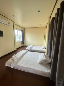 two beds in a large room with a window at โฮมสเตย์ภูมิใจ เชียงคาน ซอย 17 in Loei