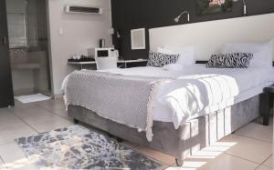 1 dormitorio con 1 cama grande con sábanas y almohadas blancas en 3 Liebeloft Guest House, en Edenvale