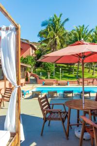 a pool with tables and chairs and an umbrella at Pousada dos Coqueiros Búzios in Búzios