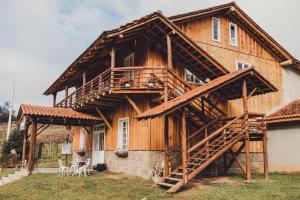 a large wooden house with a balcony and stairs at Casarão Biazolli in Farroupilha