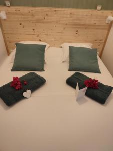a white bed with green pillows and red flowers on it at Appartement SERENITE, tout confort 2adultes 1 enft in Les Trois-Îlets