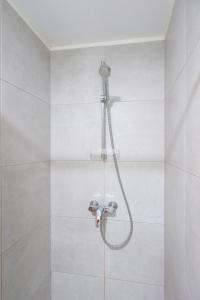 un bagno con doccia e piastrelle bianche di Eglise 26 Aparthotels a La-Roche-en-Ardenne