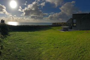a grassy field with a house and the ocean at Slate House in Ballybunion