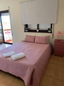 a bedroom with a pink bed with two towels on it at houses&halfhouses historic street in Caminha