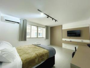 a bedroom with a bed and a flat screen tv at Studio Duque Master in Porto Alegre