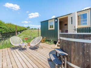 a wooden deck with chairs and a tiny house at Hot Tub Retreat - Otium Wine Estate in West Worldham