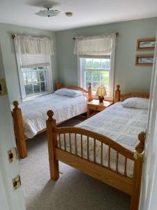 two beds in a bedroom with two windows at Cooper Hill Inn in West Dover