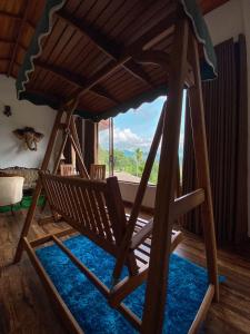 eine Holzschaukel in einem Zimmer mit einem großen Fenster in der Unterkunft Boscage Homestay in Kandy