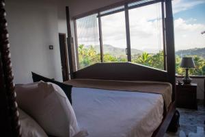 um quarto com uma cama e uma grande janela em Boscage Homestay em Kandy