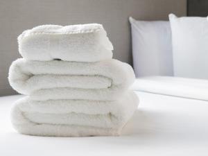 a stack of white towels sitting on top of a bed at Apartment Bloc in Birmingham