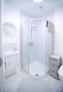 a white bathroom with a shower and a sink at Newly refurbished flat, 1 min from Galgorm resort in Cullybackey