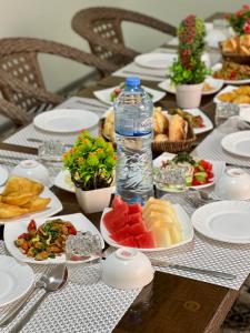 - une table avec des assiettes de nourriture et une bouteille d'eau dans l'établissement Suzani National House, à Boukhara