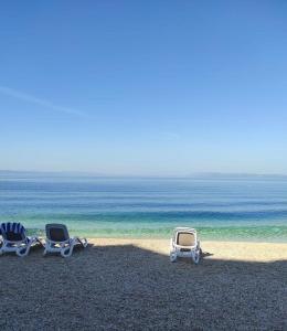 two lounge chairs on a beach near the ocean at Apartment Kastel in Podgora