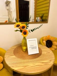 a vase of sunflowers on a table with a card at Bulacan Staycation At Urban Deca Homes Marilao in Marilao