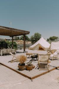 een patio met een tent en een tafel en stoelen bij Hippie house בית היפי in Mitzpe Ramon