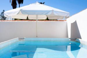 un ombrellone bianco e una piscina con ombrellone di La Perla a Chiclana de la Frontera