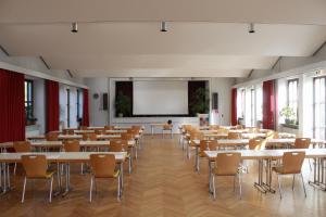 a lecture hall with tables and chairs and a projection screen at Hotel am Regenbogen in Cham