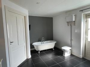 a bathroom with a white tub and a toilet at Luxe vakantiewoning op de Goudsberg in Lunteren +8 photos