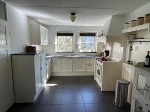 a kitchen with white cabinets and a tile floor at Luxe vakantiewoning op de Goudsberg in Lunteren