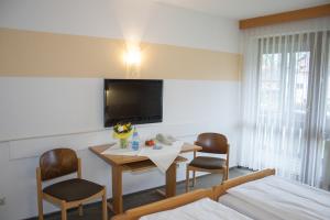 a room with a table and two chairs and a tv at Hotel am Regenbogen in Cham