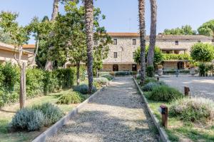 un jardín frente a un edificio con palmeras en Algioja Apartment with Pool & Parking, en Passignano sul Trasimeno