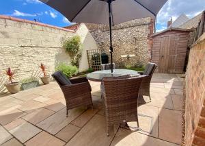 a table and chairs with an umbrella on a patio at Lapwing Cottage Docking in Docking