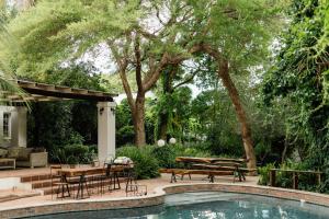 a backyard with a pool and a table and benches at Upington African Vineyard Boutique Hotel & SPA in Kanoneiland