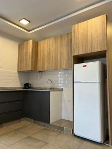 a kitchen with a white refrigerator and wooden cabinets at MODERNO DEPARTAMENTO PARA 3-4 PERSONAS, MUY BIEN UBICADO in Santiago del Estero