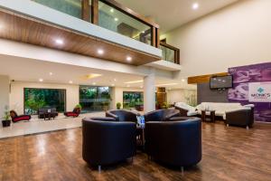 sala de estar de planta abierta con sillas de cuero y TV en Monk's Nirvanaa Hotel & Resort en Indore