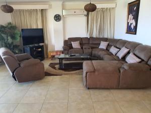 ein Wohnzimmer mit einem Sofa, Stühlen und einem TV in der Unterkunft Your Perfect Getaway with a Breathtaking Beach View in Ain Suchna