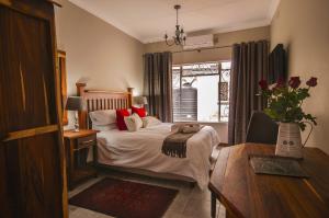 a bedroom with a bed and a table and a window at Cornerstone B&B Kroonstad in Kroonstad