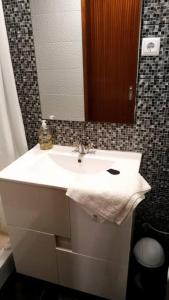 y baño con lavabo blanco y espejo. en Casa das Matriarcas - Casa da Avó Benvinda, en Belmonte