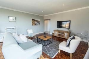 uma sala de estar com um sofá branco e uma televisão em Stylish Apartment With Park View em Port Elizabeth