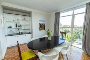 uma sala de jantar com uma mesa preta e cadeiras brancas em Stylish Apartment With Park View em Port Elizabeth